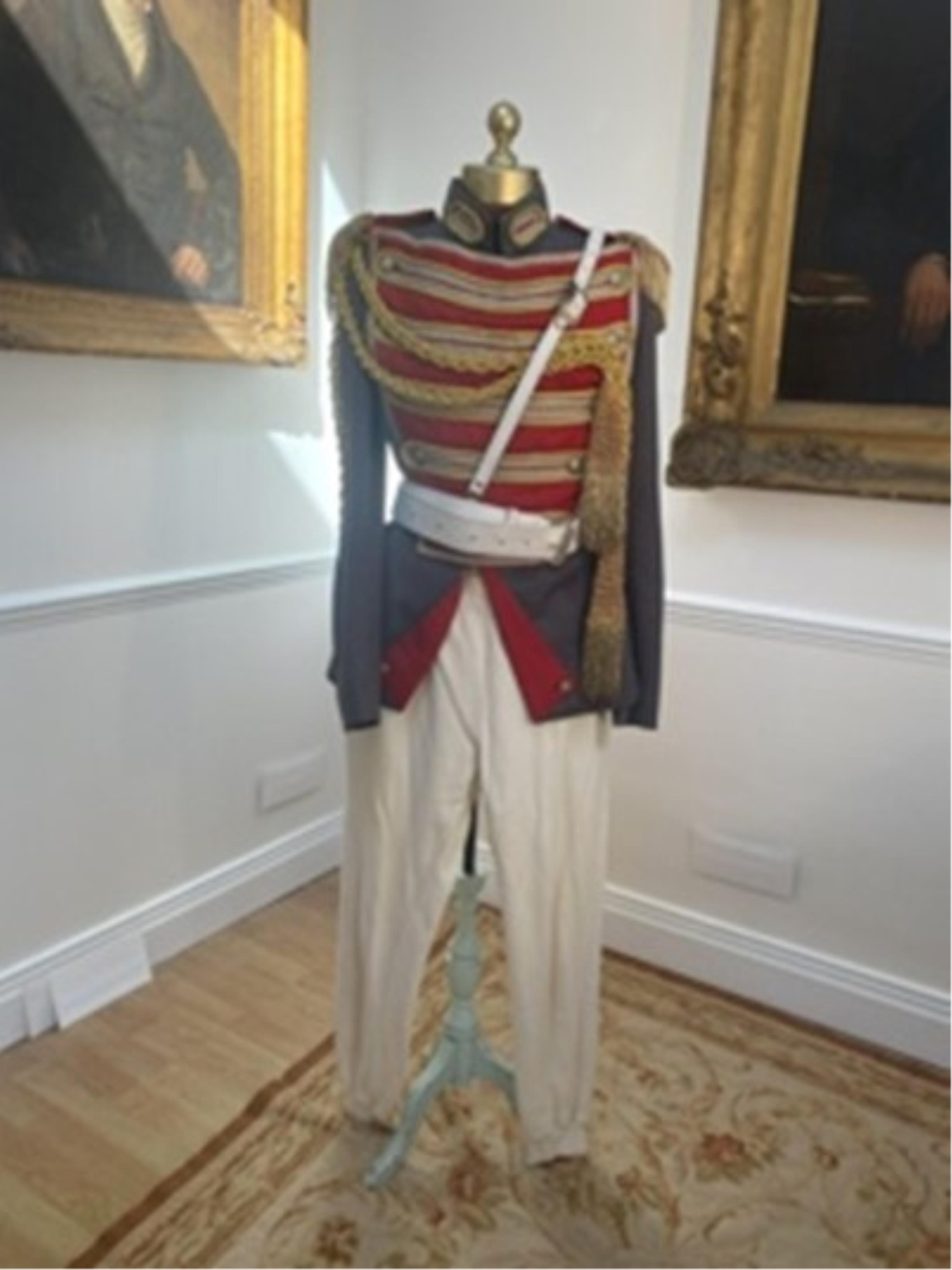 A military style uniform with elaborate trim and epilates and other accessories, cream leggings and black velvet over leggings, labelled The Netherlands Opera